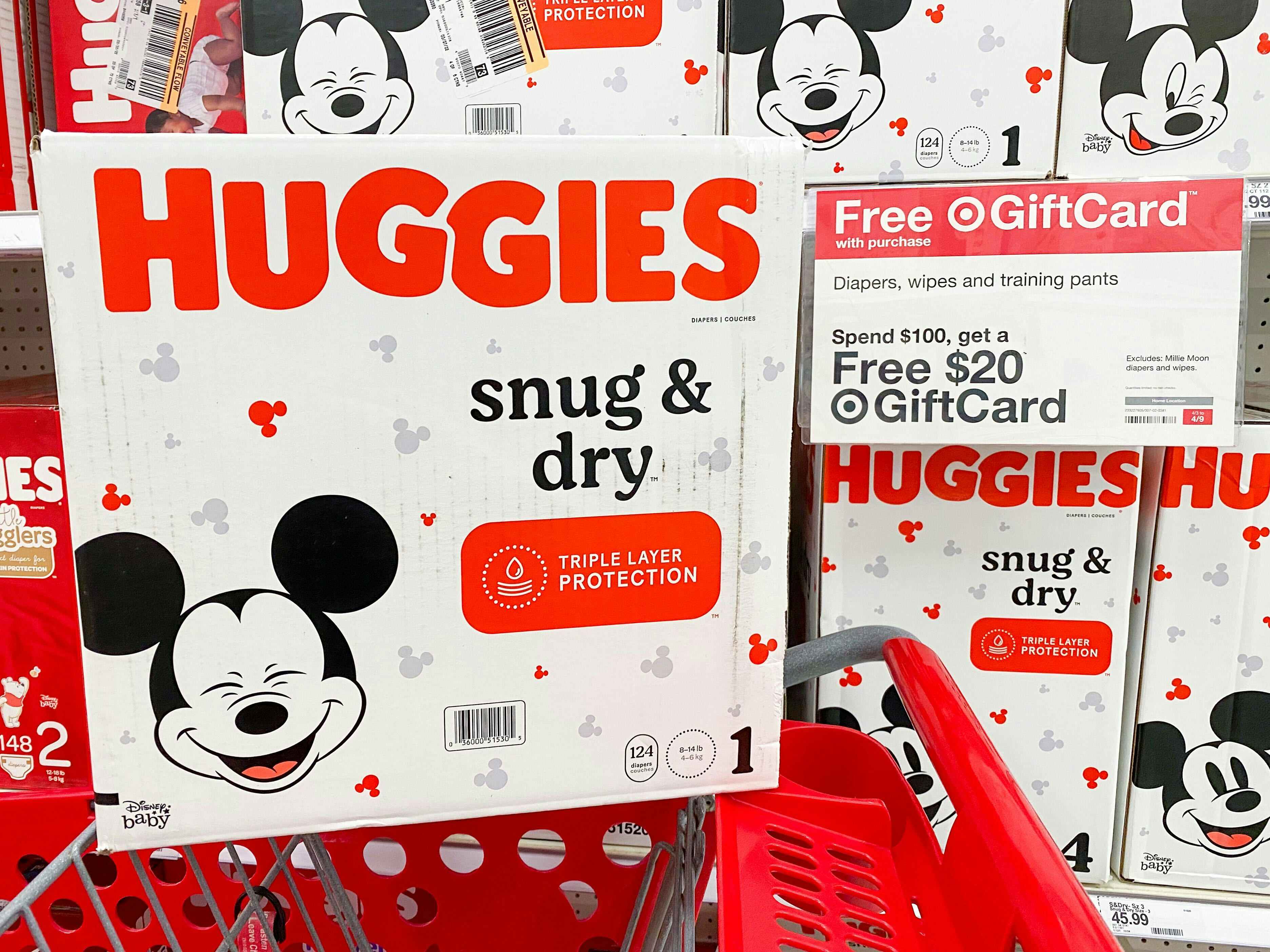 A box of Huggies Snug & Dry diapers sitting on a Target shopping cart in front of a sign advertising a Free $20 Target gift card when you...