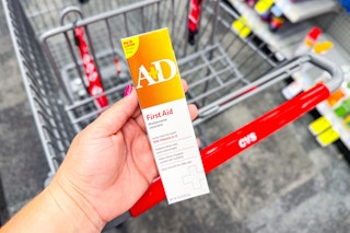 person holding a&d first aid ointment over a cvs cart