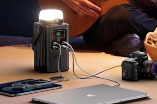 The Camping Portable Power Station 198.4Wh (62000mAh) at a campsite charing electronics.