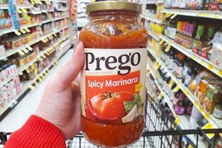 A hand holding Prego pasta sauce in Safeway
