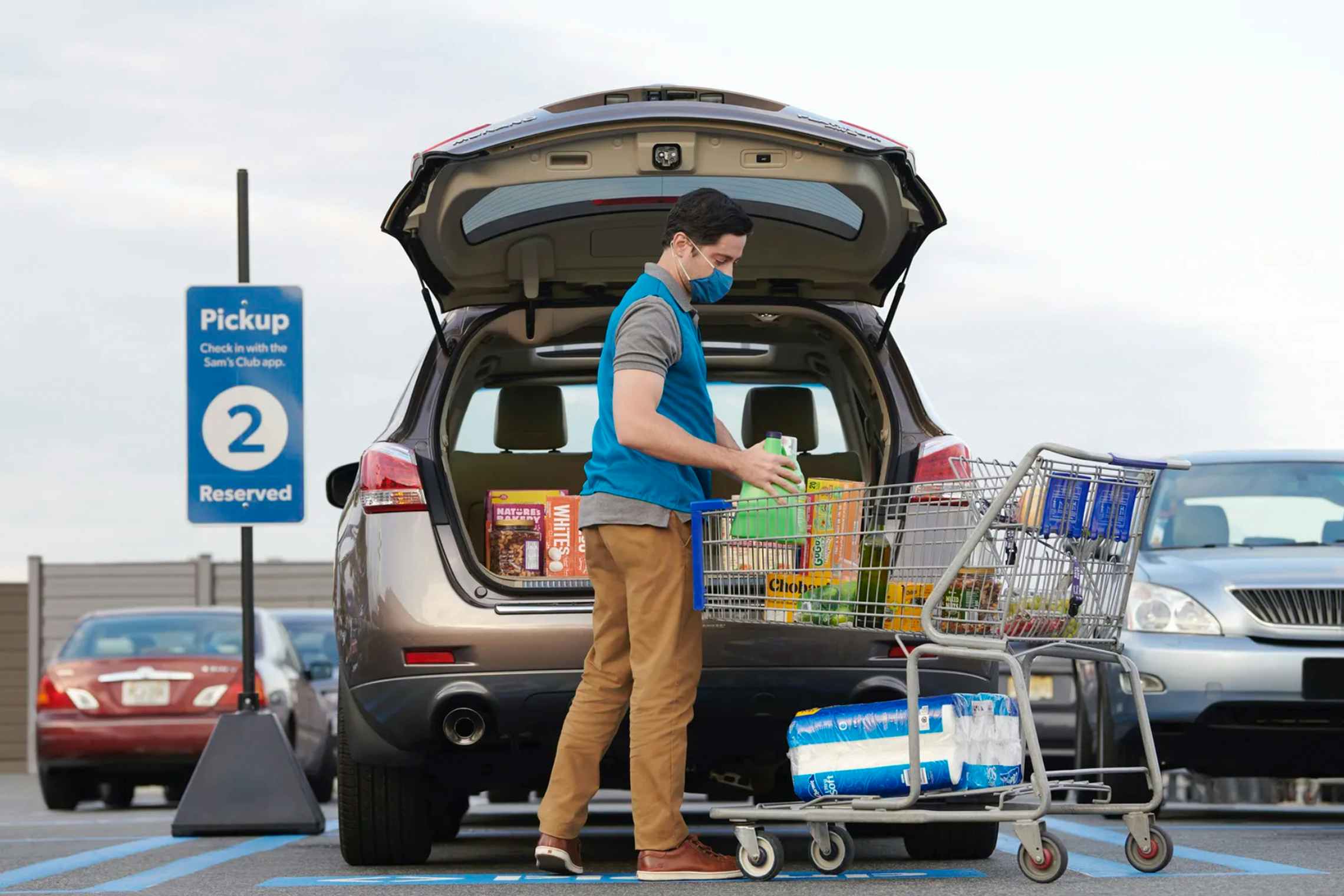 A Sam's Club employee putting groceries into the back of an SUV