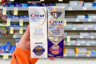 hand holding two tubes of crest premium toothpaste at walgreens