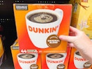A person's hand taking a box of Dunkin K-Cups from a shelf at Walmart.