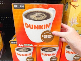 A person's hand taking a box of Dunkin K-Cups from a shelf at Walmart.