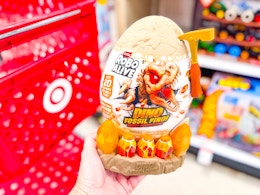 hand holding the Robo Alive Dino Fossil Find egg in front of a Target cart