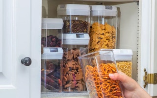 someone putting a food storage container in their cupboard