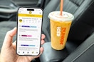 a person holding up the kcl app with a dunkin iced coffee in the background