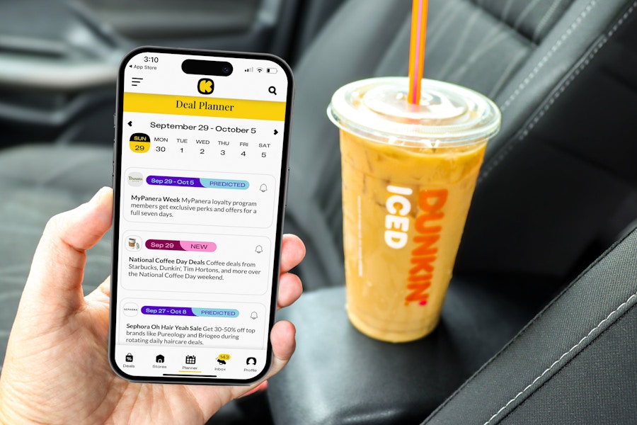 a person holding up the kcl app with a dunkin iced coffee in the background