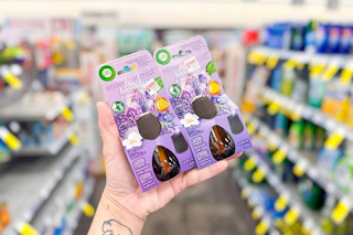 person holding air wick essential mist refills in an aisle