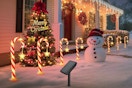RVZHI Solar Lights Outdoor Christmas Candy Canes outside a house in the winter snow.