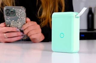 person using green label maker printer from their phone bluetooth