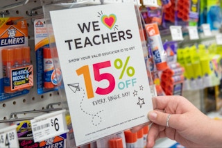 A person holding up a michaels teacher discount sign 