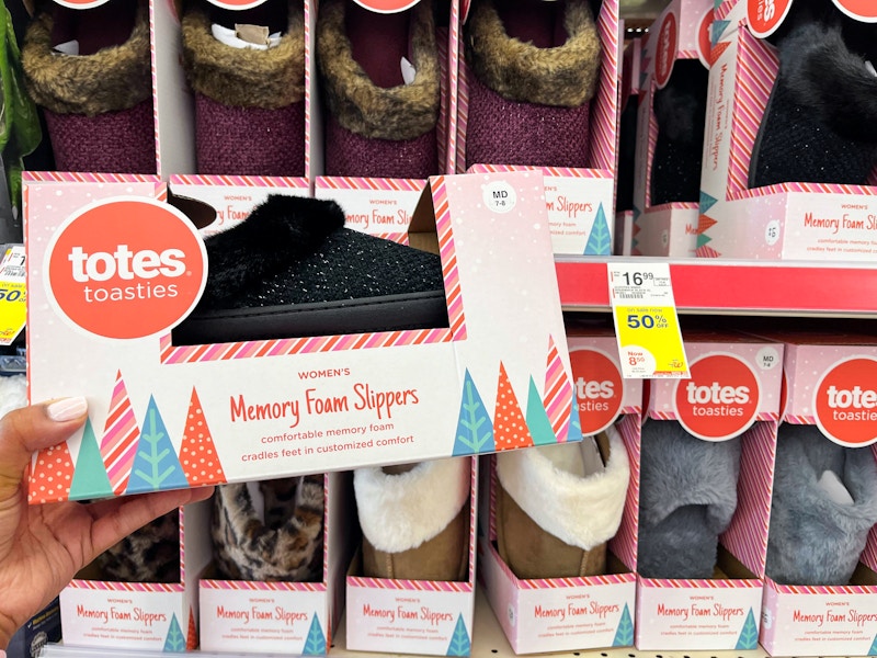 hand holding pair of slippers next to sale tag on store shelf