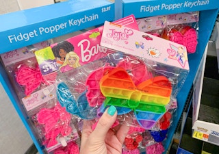 three fidget popper keychains held in front of fidget popper display