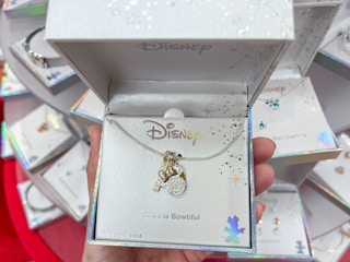A Disney necklace held out by hand in front of other Disney jewelry