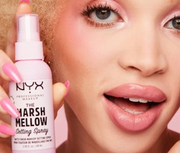 a person holding a pink bottle of makeup spray