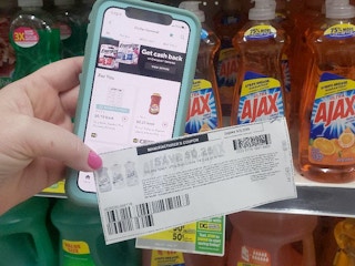 A person holding a smartphone with the ibotta app and a coupon in their hand.
