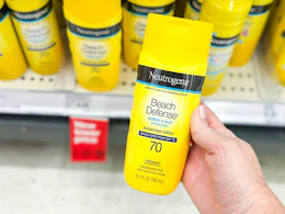 hand holding a bottle of neutrogena sunscreen in front of a target shelf
