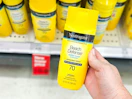 hand holding a bottle of neutrogena sunscreen in front of a target shelf