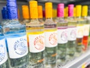 Hand holding a mango flavor of White Claw vodka in front of the White Claw Vodka shelf