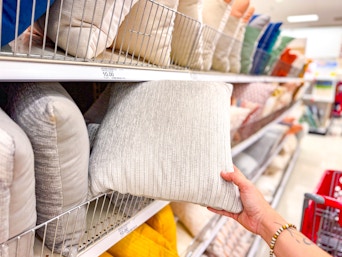 hand grabbing a throw pillow off a target shelf