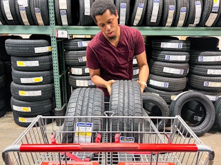Person placing two tires into a Bj's shopping cart