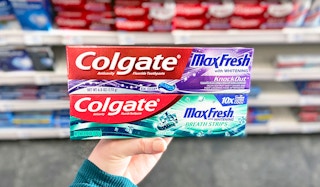 hand holding two boxes of Colgate toothpaste