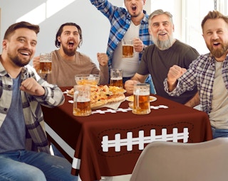 people sitting at a table with a football-themed tablecloth