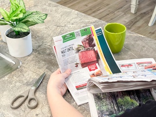 a person pulling coupon insert out of a newspaper