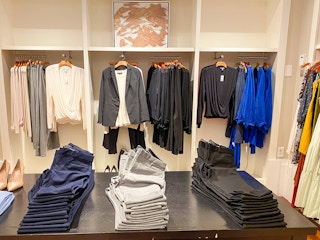 pants on a table with womens shirts and pants on racks in the background in banana republic