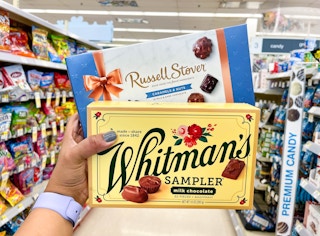 hand holding box of Russell Stover & Whitman's chocolate