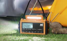a yellow and black emergency radio on grass next to a tent