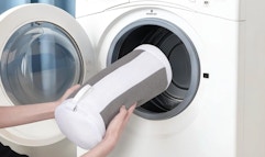 a person putting a shoe washing bag in a washer 