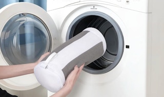 a person putting a shoe washing bag in a washer