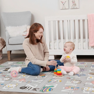 a mother and baby playing on a foam abc playmat