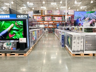 an aisle of TVs inside the Costco Electronics section.