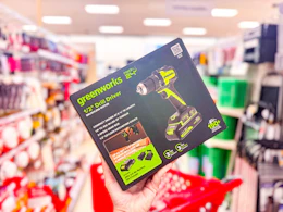 hand holding greenworks drill/driver in front of target shelf