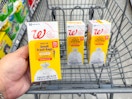 hand holding walgreens trash bags pack and two in cart