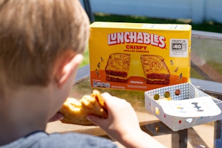 a child eating a lunchable grilled cheese sandwich outside on patio table