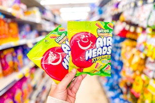 hand holding 2 bags of air heads candy
