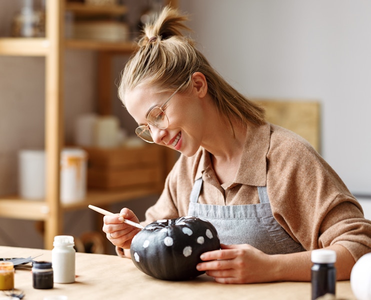 woman painting polka dots on black and white pumpkin