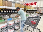 a man filling up a bag in the winco bulk foods area next to a cart