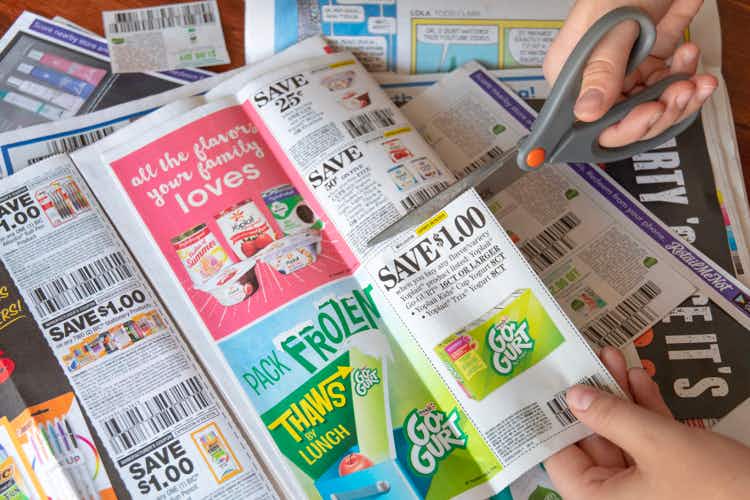 Person using scissors to cut a $1.00 coupon for Yoplait Go-Gurt