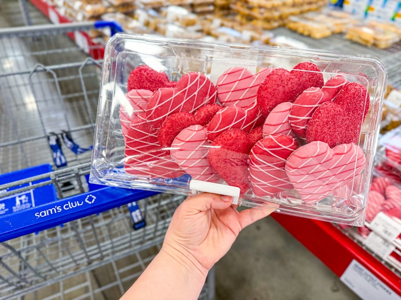 person holding a package of heart shaped cutout cookies over a cart