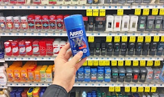 A hand holding Arrid deodorant in a store aisle.