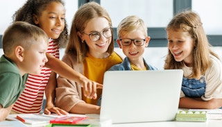 teacher with students learning on laptop at school