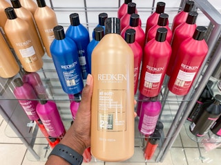 someone holding a liter-sized redken shampoo