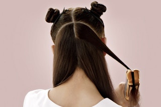 a woman straightening her hair with the dyson airstrait