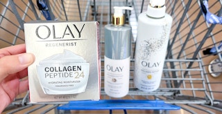 person holding olay collagen peptide moisturizer alongside other olay products in walmart cart