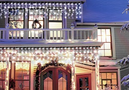 icicle lights on the front of a house with Christmas decorations